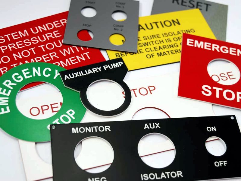 A sheet of custom-cut, multi-coloured lamacoid tags for electrical panel identification.