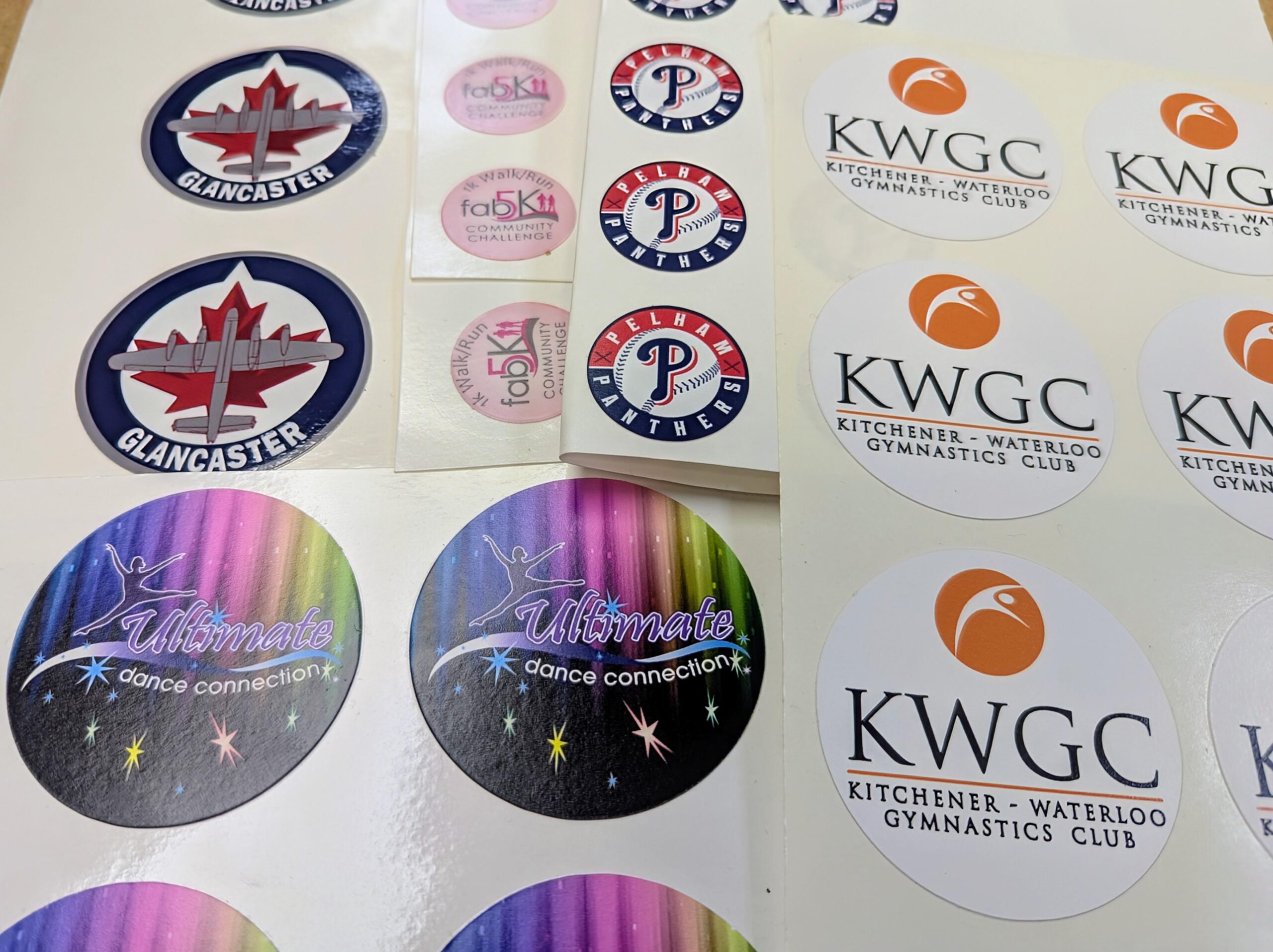 A sheet of custom-printed, precision-cut decals for sports helmets and award medal inserts.