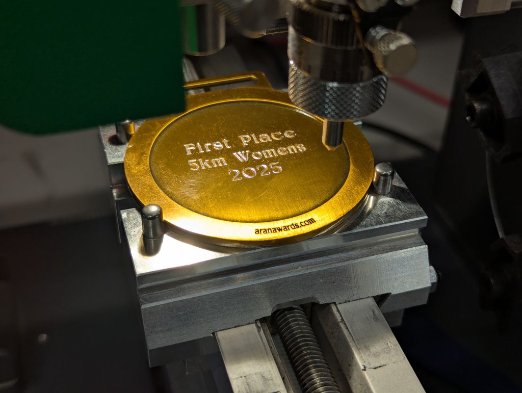 Gold sports medal being cnc engraved from Aran Awards
