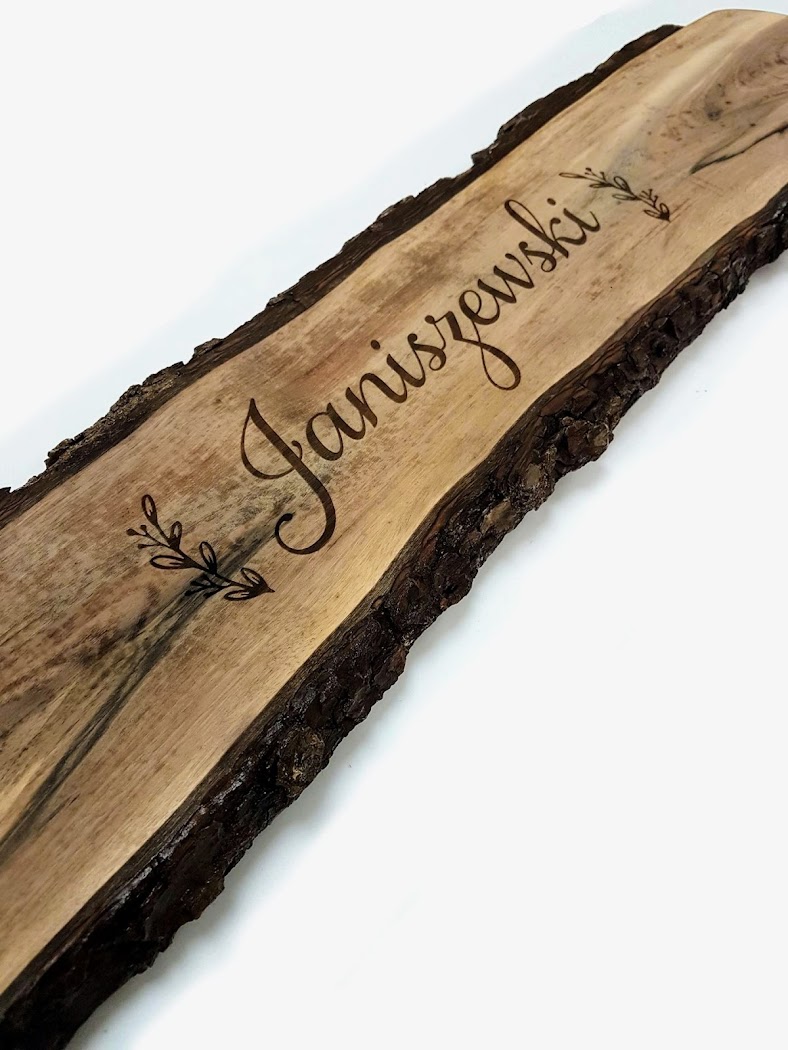 Live-edge wood engraving showing decorative script-style lettering
